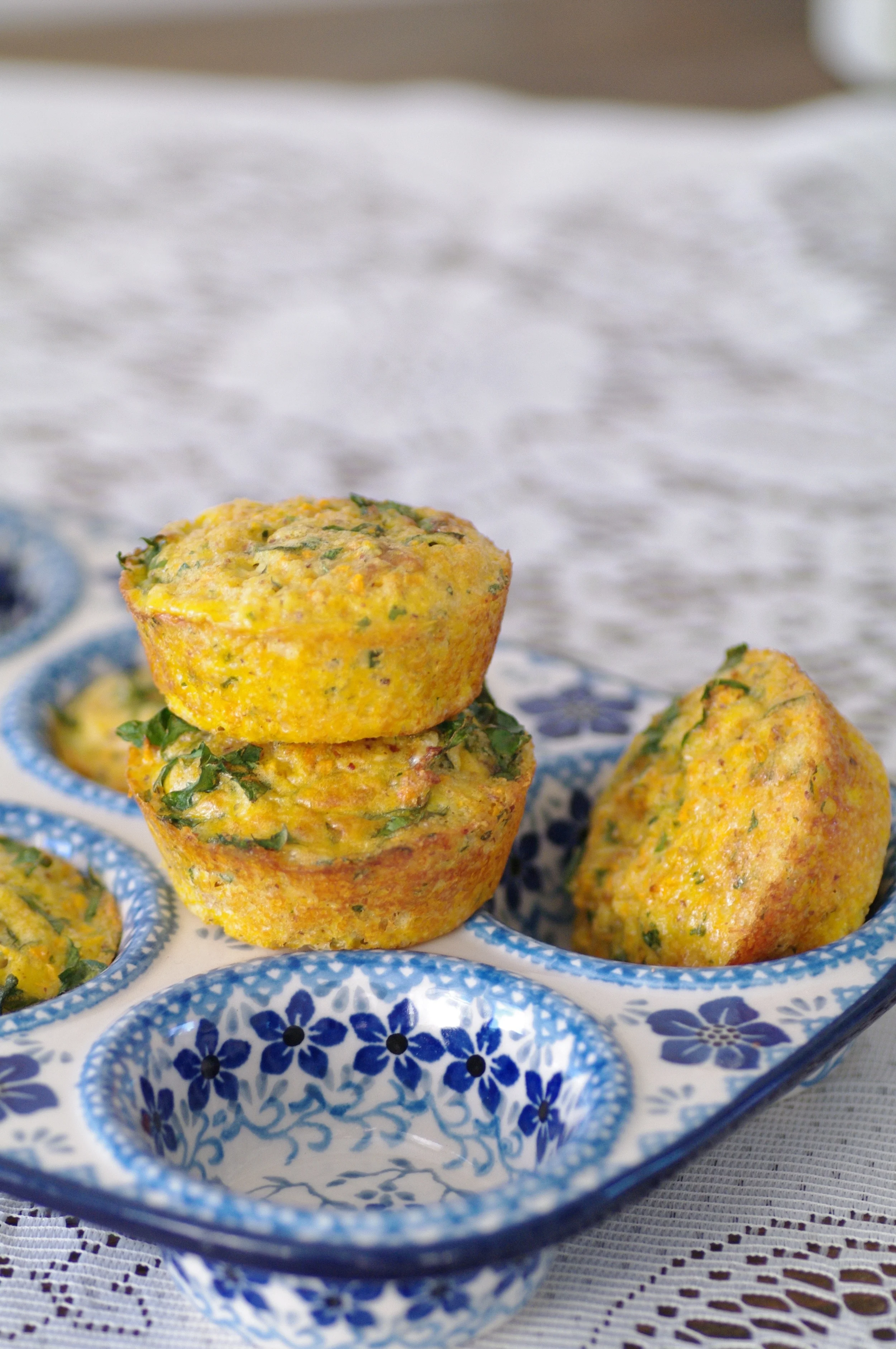 Stacked savory muffins in a blue and white floral baking dish with warm yellow and blue tones, cozy communal mood